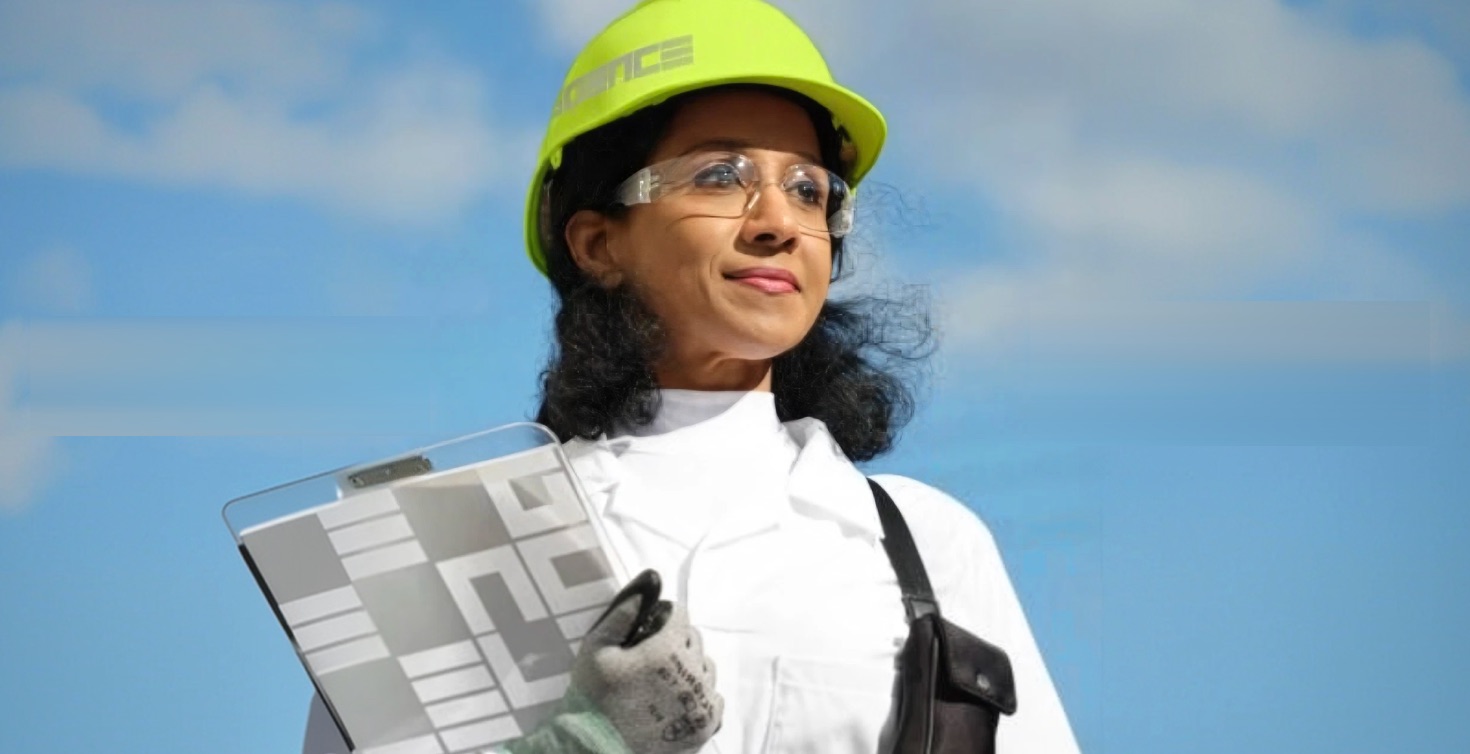 Home-service technician in a lime hard hat, clipboard in hand, against a blue sky